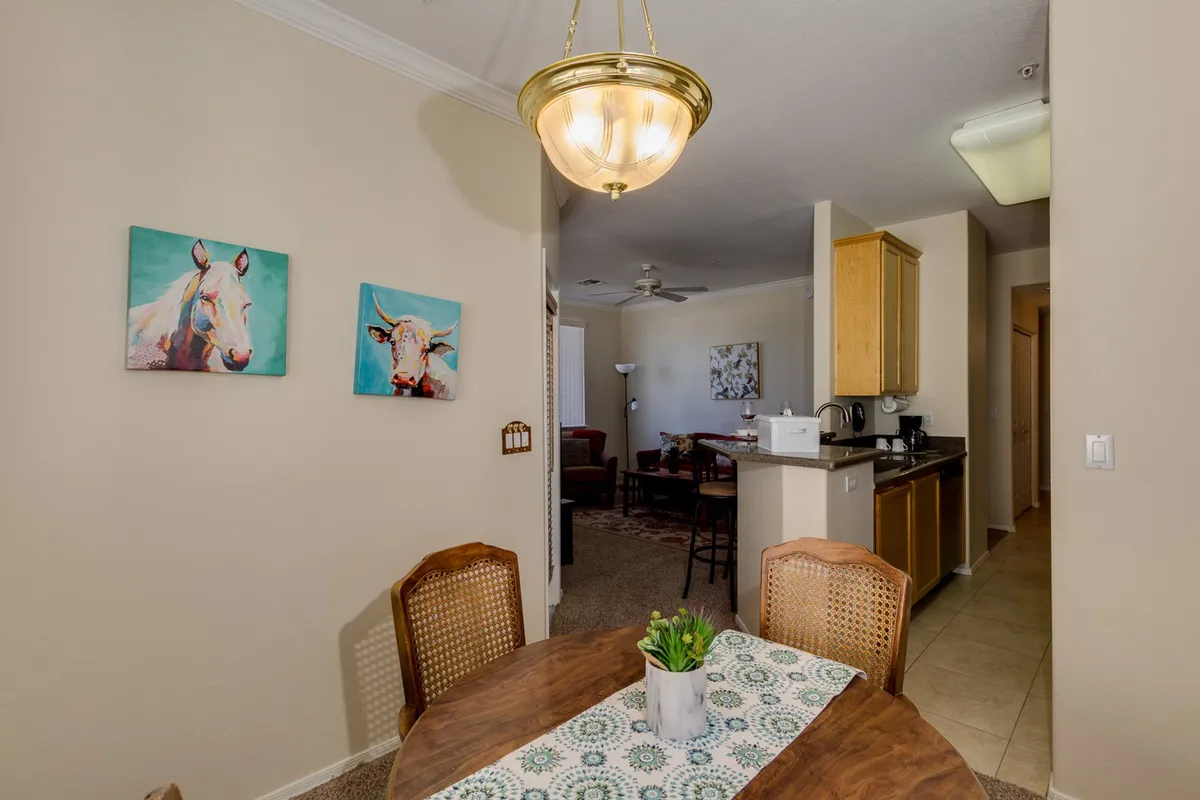 A bright dining area with a sizable table, eye-catching wall art, and a view into the kitchen. The setting is ideal for shared meals, work sessions, or casual gatherings, exuding a welcoming atmosphere.