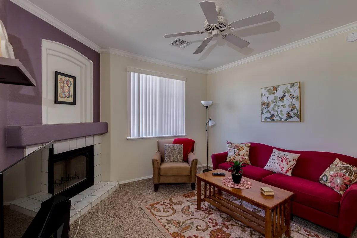 A cozy living area featuring a red couch and fireplace, inviting for relaxation after a day out. Decorative artwork and a coffee table add to the welcoming ambiance, hinting at a comfortable space to unwind.