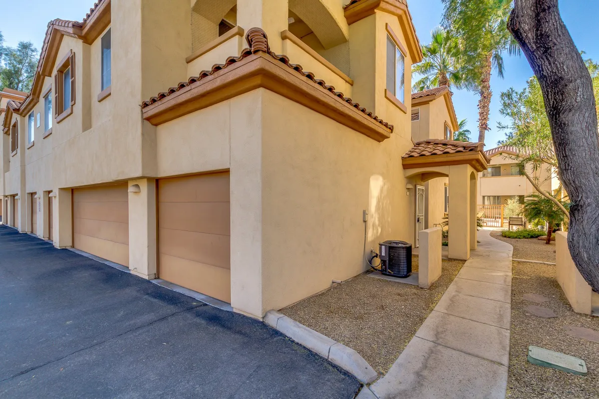 The exterior view showcases garage doors, a landscaped walkway, and lush greenery, offering an alternate angle of the property’s entry points. The environment feels both private and inviting, suggesting a peaceful transition from outside in.