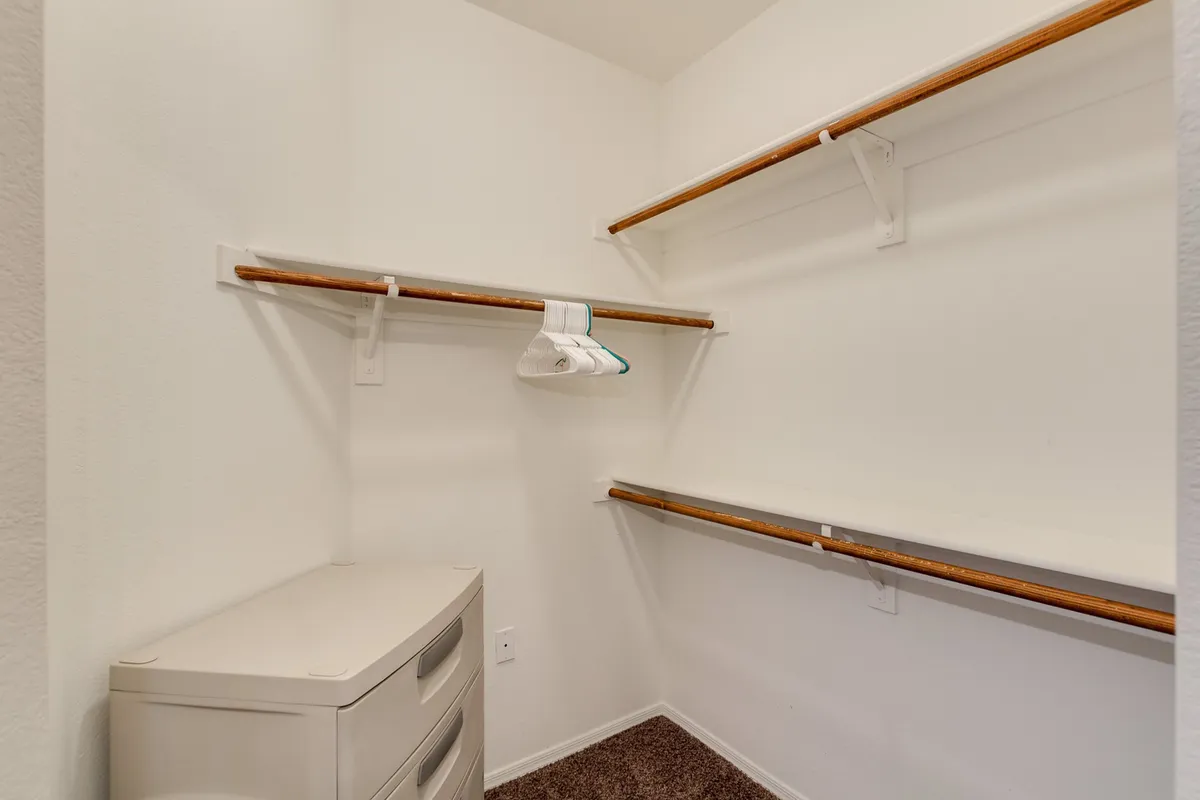 A walk-in closet with neatly arranged shelves, a storage unit, and a hanger, all creating a sense of organization and spaciousness.