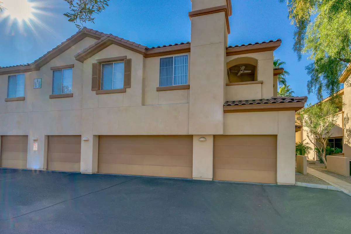 This exterior image prominently features garage doors, a second-floor balcony, and appealing architectural details. The driveway leads directly to the private garages, capturing the sense of convenient, secure entry mentioned in the section. The clean lines and landscaping add to the sense of a welcoming and exclusive arrival point.