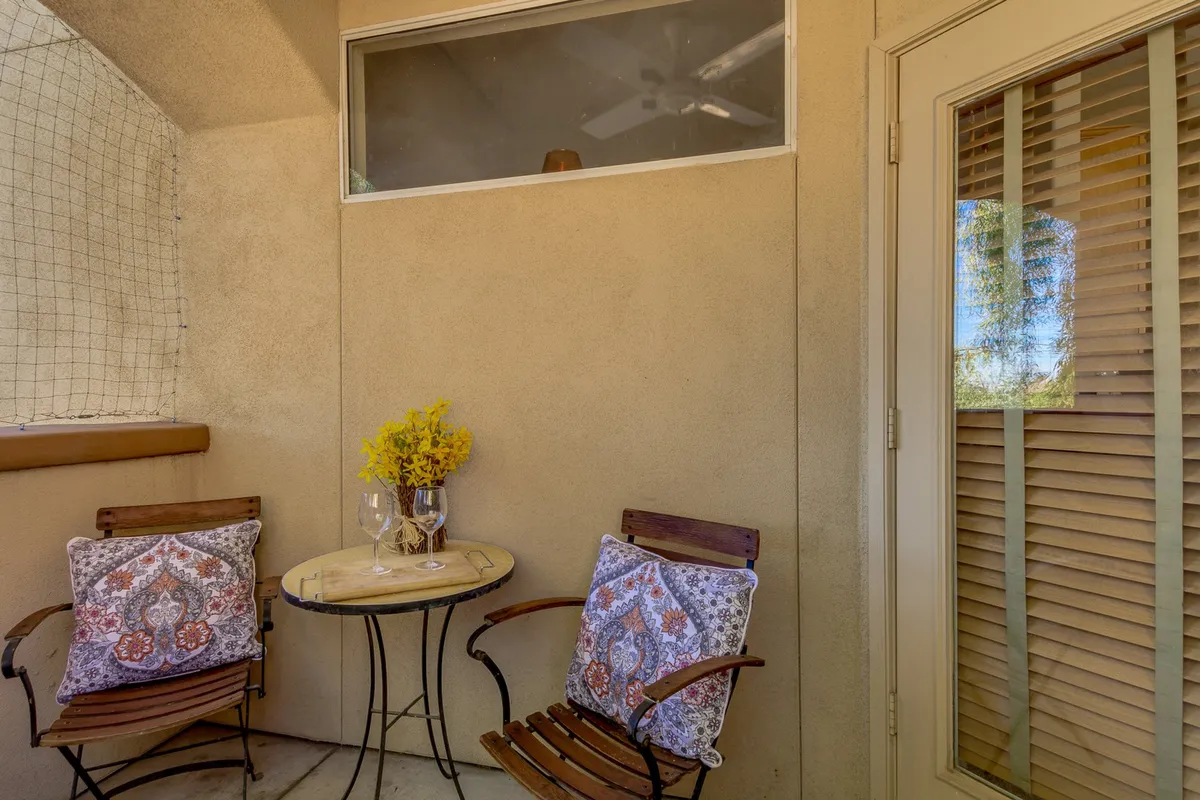 A sunlit room with wooden chairs and a round table, surrounded by decorative pillows and flowers. The warm, welcoming environment suggests a perfect place for morning coffee or recapping the game with friends.